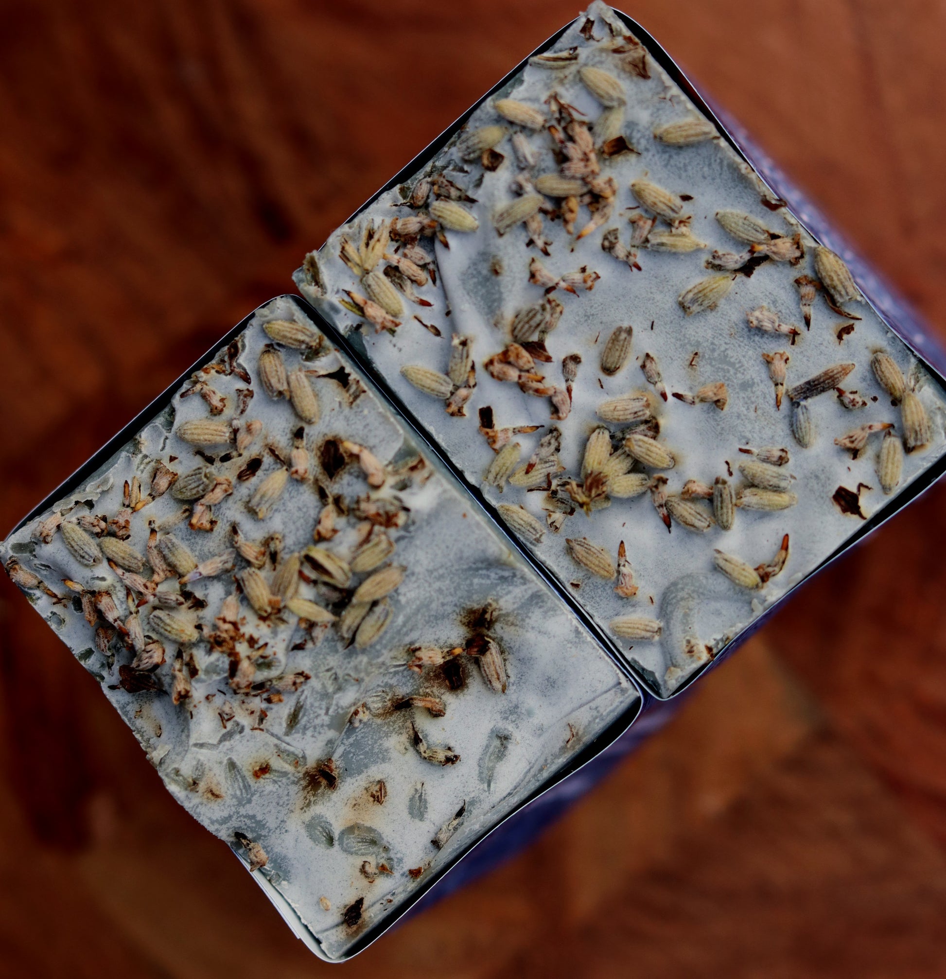 Close-up of a bar of soap with visible herbs on a brown background
